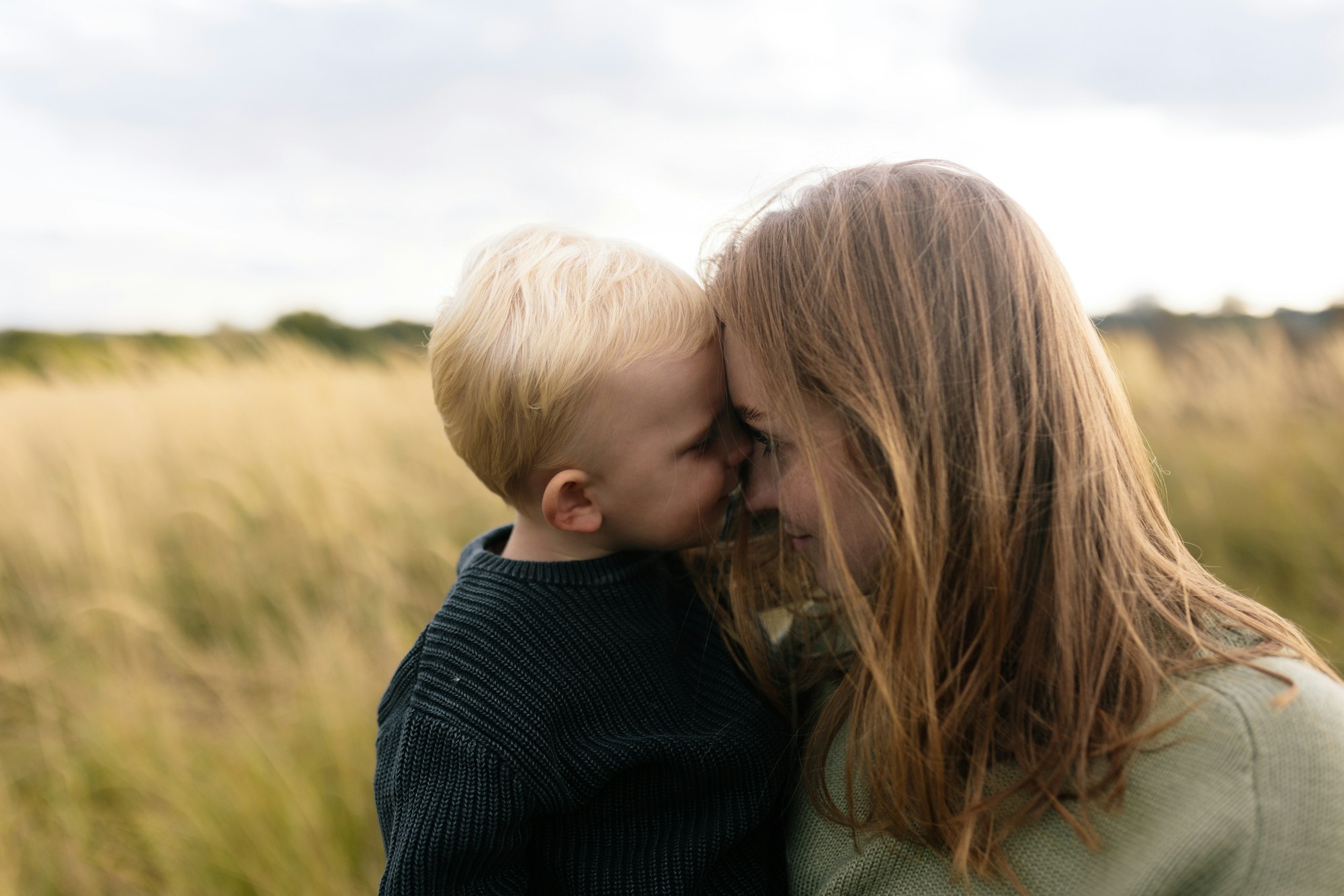 A mother and child sharing a quiet moment together in a summer field